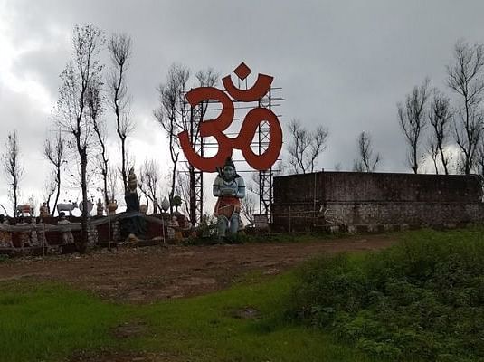 A view of the Nilkantheshwar Mandir with a large Om symbol in the background.